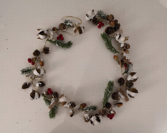 Ghirlanda innevata con foglie, pigne e fiori di cotrone