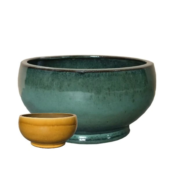 Vaso Decorativo Rotondo Noble Bowl Low in Ceramica Smaltata di Mega Collections (distribuita da Floral Garden). Questo elemento d'arredo basso e svasato (Bowl Shape) si sviluppa su una base solida con piedistallo pronunciato, ideale per dare vita a composizioni botaniche espanse o ospitare micro-paesaggi succulenti. In due colori su sfondo bianco.